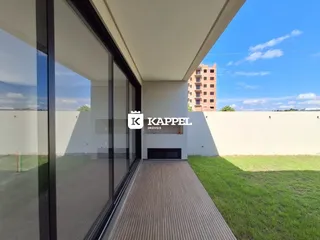 Vista externa de um imóvel com deck e muro branco.