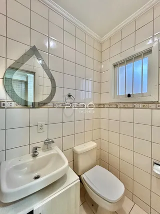 Banheiro com azulejos brancos e louças sanitárias