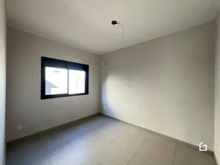 Ambiente interno de uma sala com piso de cerâmica e janela.