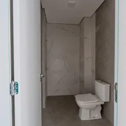 Banheiro com paredes em mármore claro e vaso sanitário branco.