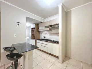 Vista interna de uma cozinha com armários brancos e piso de cerâmica.