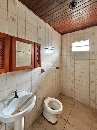 Foto de um banheiro com paredes de azulejo branco e piso de cerâmica.