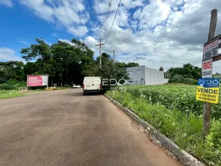 Vista externa de uma propriedade rural com uma estrada e vegetação ao fundo.