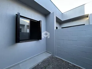 Fachada externa de uma residência em Lajeado, Brasil, com parede cinza clara e piso de cascalho.