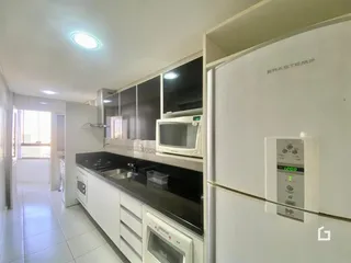 Foto da cozinha com armários brancos e bancadas escuras.