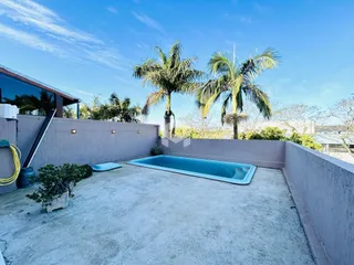 Área externa com piscina e paisagem de palmeiras.