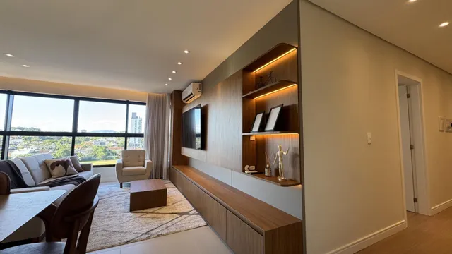 Sala de estar com sofá e grande janela com vista da cidade.