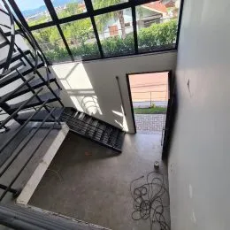 Hall de acesso com escada e vista para o exterior.
