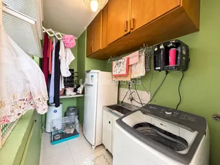 Interior de uma cozinha com armários de madeira e máquinas de lavar roupa.