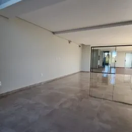 Vista interna de um ambiente com paredes brancas e piso de concreto.