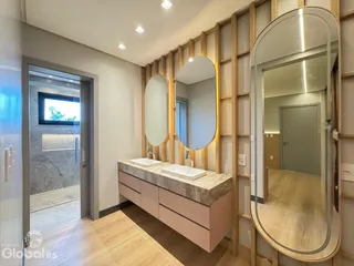 Ambiente de banheiro com bancadas e espelhos decorados com painéis de madeira.