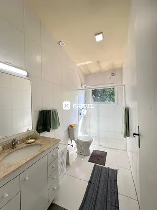 Banheiro com revestimento branco e bancada clara.