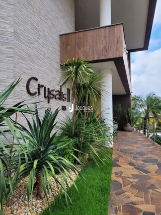 Fachada de um imóvel com paisagismo verde e calçada de tijolos.