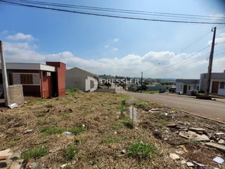 Vista externa de uma propriedade com terreno gramado e construções ao fundo.