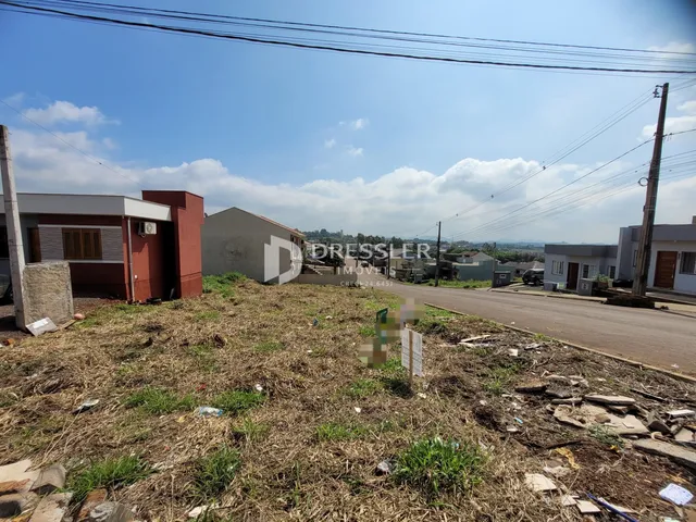 Vista externa de uma propriedade com terreno gramado e construções ao fundo.
