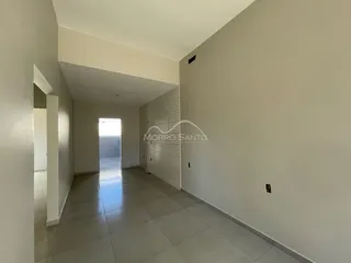 Foto de um corredor interno de uma residência com paredes brancas e piso claro.