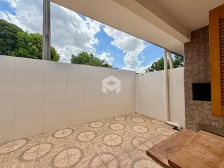 Vista de uma área externa com piso de cerâmica e parede branca.