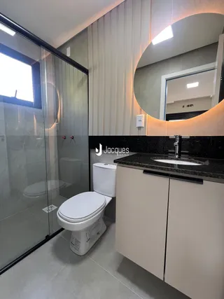 Banheiro moderno com box de vidro e louças brancas em imóvel no Brasil.