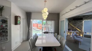 Sala de jantar com mesa branca e cortinas claras.