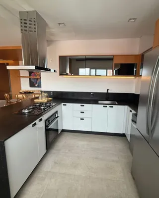 Foto de uma cozinha moderna com armários brancos e bancadas escuras.