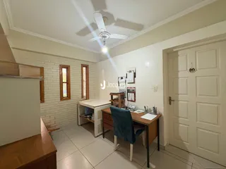 Interior de uma sala com paredes de tijolo branco e piso claro.