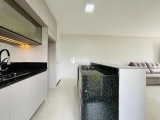Vista da cozinha moderna com armários brancos e ilha escura.