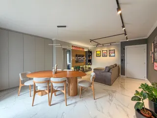 Sala de estar e jantar com piso de mármore claro e móveis de madeira.