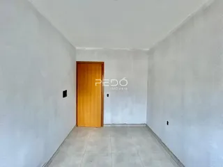 Corredor interno de uma residência com paredes brancas e piso de cerâmica.