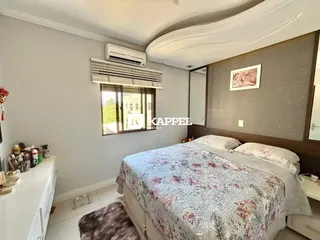 Quarto com cama e janela com persiana e ar-condicionado.