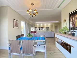 Uma foto da sala de jantar com mesa de vidro e cadeiras de vime.