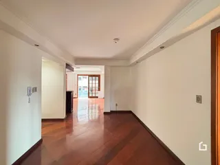 Corredor interno com piso de madeira polida e paredes brancas.