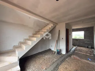 Vista interna de uma área com escadaria e paredes em construção.