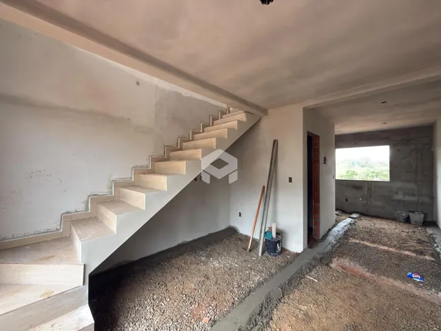 Vista interna de uma área com escadaria e paredes em construção.