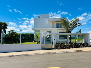 Fachada de uma casa moderna branca em Lajeado, Brasil, com paisagismo frontal.