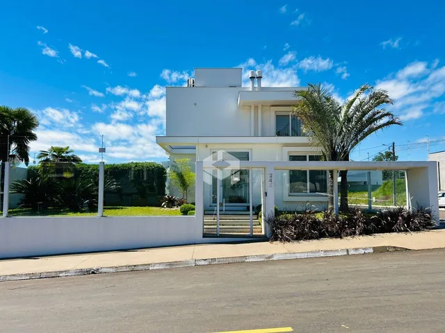 Fachada de uma casa moderna branca em Lajeado, Brasil, com paisagismo frontal.