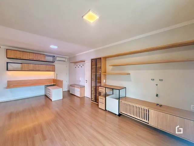 Ambiente interno de uma sala com piso de madeira e armários planejados.