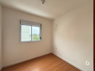 Ambiente interno de uma sala com piso de madeira e janela.