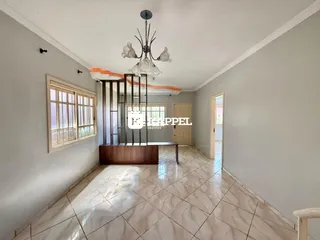 Esta é uma sala de estar ampla com piso de porcelanato e grandes janelas.