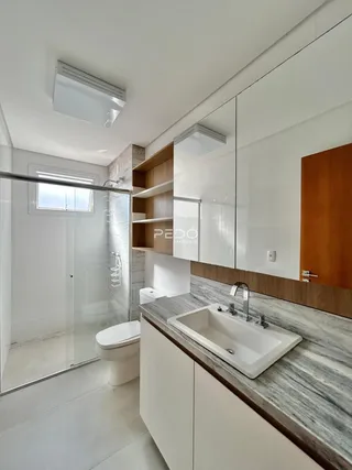 Banheiro moderno com box de vidro e bancada de mármore.