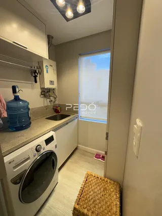 Interior de uma cozinha com máquina de lavar roupa e armários brancos.