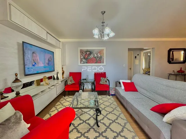 Sala de estar com sofá cinza e cadeiras vermelhas em um imóvel no Brasil.