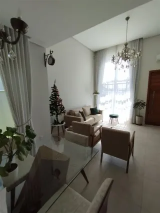 Sala de estar iluminada com cortinas claras e lustre.