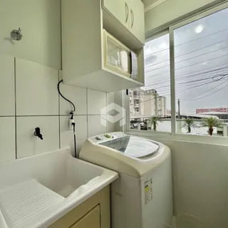 Foto de um banheiro com azulejos brancos e máquina de lavar roupa.