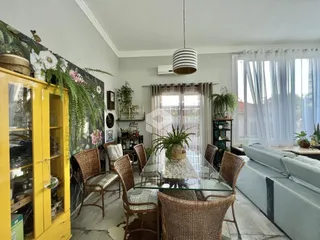 Sala de jantar com mesa de vidro e cadeiras de vime.