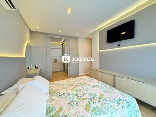 Um quarto moderno com cama grande e televisão montada na parede.