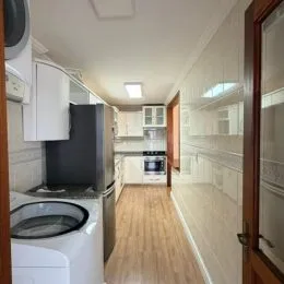 Corredor interno com piso de madeira e armários brancos.