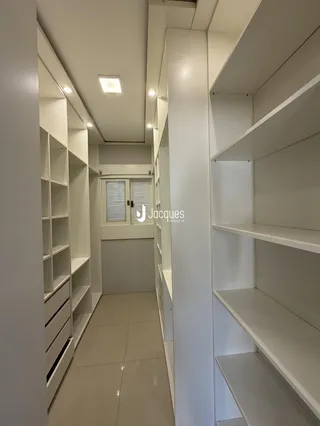 Corredor interno de um imóvel moderno com armários embutidos brancos.