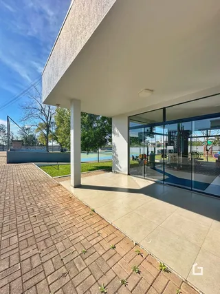 Fachada de uma residência com piso de tijolos e portas de vidro.