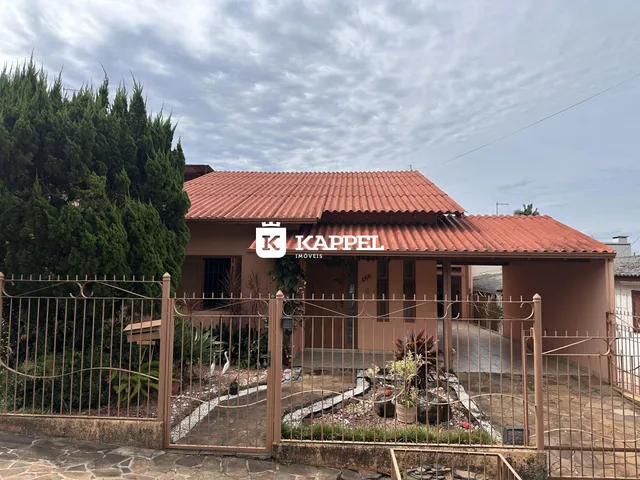 Fachada de uma residência com telhado de telhas vermelhas e cerca frontal em Lajeado.