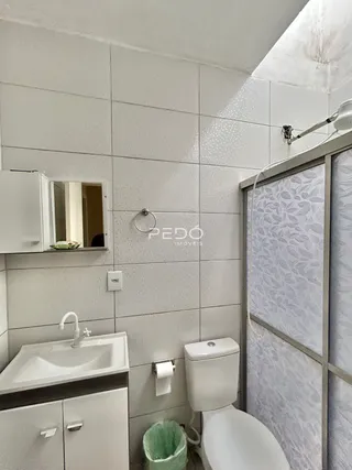 Foto de um banheiro interno com louças sanitárias brancas.